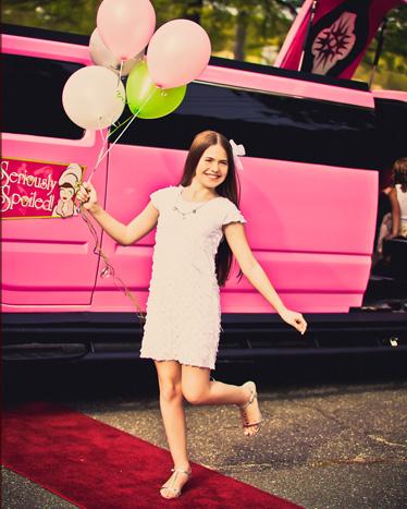 Deluxe indulgence girl holding balloons on red carpet limouzine in the background